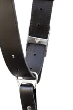 Close-up of a black leather camera harness showing silver connectors, buckle detail, and adjustment holes.