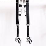 Black GenuineStrap SW Edition leather camera strap with white inner padding, showing D-ring ends hanging over wooden beam