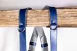 Close-up of Blue Shanty harness shoulder attachment showing metal D-ring connector with rivet detail and grey fabric padding visible on center strap