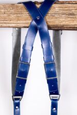 Detail shot of Blue Shanty harness center X-strap showing layered leather segments with metal square connectors, rivets, and navy and grey leather color blocking