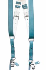 Blue Sirocco leather camera harness laid flat on weathered wood displaying dual turquoise shoulder straps with metal D-rings, white center strap with teal leather accent bands, multiple adjustable segments, white stitching detail, and metal carabiner attachments with leather tags at base