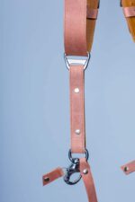 Close-up detail of Brown Siena harness center strap showing suede-textured brown leather, darker overlay band, metal connector hardware with rivet detail, and white stitch accents