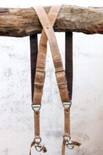 Front view of Brown Wild West Vintage harness showing complete X-design with tan leather shoulder straps, black textured center strap with brown leather accent bands, metal connectors, and carabiner clip attachments at base