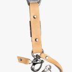 Close-up of light brown leather camera strap end with silver clasp and rivet details on a light background.