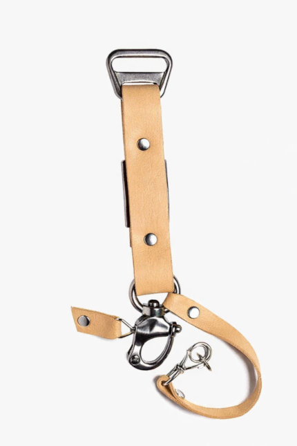 Close-up of light brown leather camera strap end with silver clasp and rivet details on a light background.