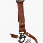 Close-up of brown leather camera strap end with silver clasp and rivet details on a light background.