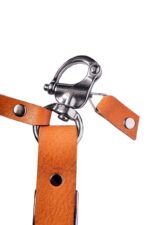 Tan leather camera harness slider with swivel clasp attached, strap detail on white background