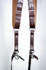 Close-up of dark brown leather dual harness straps with metal clips and stitching detail.