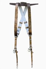 Full view of the gold embossed leather dual camera harness hanging from a rustic iron bar against a white background, showing the complete front view with two wide crinkled metallic gold shoulder straps, white leather back panel with X-cross design, branded "GENUINESTRAP" connectors, adjustable buckles, snap shackle clips, and lobster claw clasps at each end.