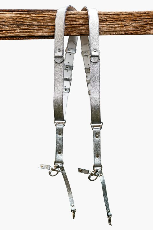 Complete front display of Grey Flower Embossed leather camera harness showing dual silver-grey shoulder straps with embossed floral design, light to dark grey ombre center strap, metal D-rings, square connectors, adjustable leather accent bands, and carabiner clips with leather tags