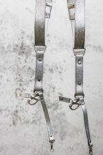 Full length detail of Grey Flower Embossed harness showing embossed flower design on all straps, metal square connectors on center strap, engraved metal hardware, rivets, and carabiner clips with leather attachment tags