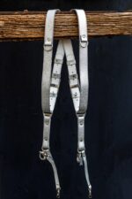 Side profile view of Grey Flower Embossed harness on weathered wood showing the ornate embossed flower pattern throughout all straps, metal hardware, and complete X-harness structure with carabiner attachments
