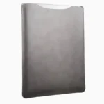 Grey leather MacBook sleeve photographed at angle, showing smooth leather surface, contoured shape, and hand-opening top edge