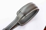 Grey leather strap detail showing padded loop and contrast stitching.