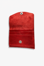Open red leather battery and SD card holder with multiple card slots, snap closure, and suede interior on a light gray background.