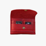 Red leather battery and SD card holder opened to show storage slots with memory cards inside on a light gray background.