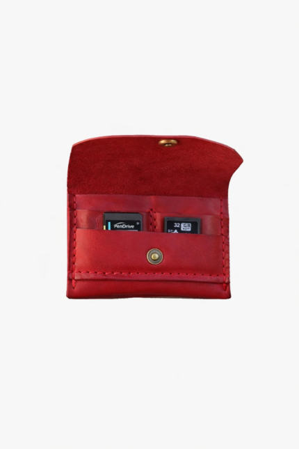 Red leather battery and SD card holder opened to show storage slots with memory cards inside on a light gray background.