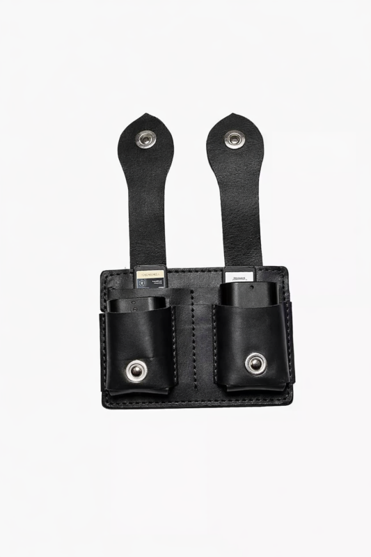 Black leather dual battery holder with two hanging tabs on a light background.