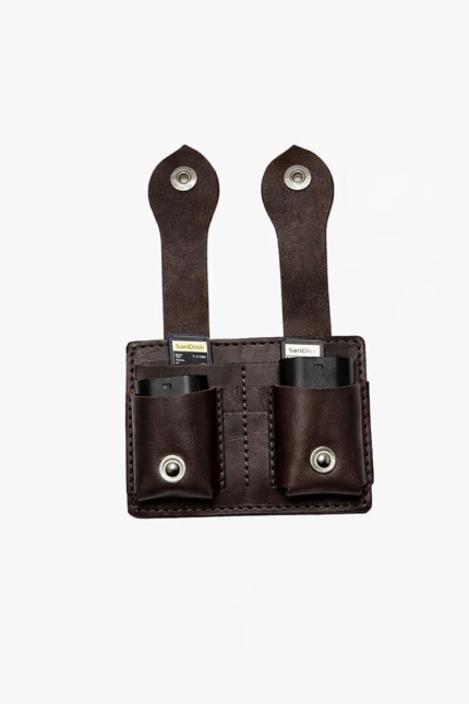 Dark brown leather dual battery holder with two hanging tabs on a light background.
