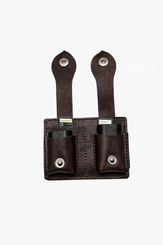 Dark brown leather dual battery holder with two hanging tabs on a light background.