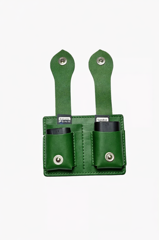 Green leather dual battery holder with two hanging tabs on a light background.