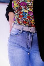 Cintura grigia glitter indossata su jeans, dettaglio vita e fibbia