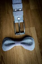 Papillon grigio glitter con dettaglio clip bretelle su tavolo in legno