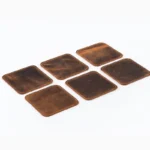 Six square brown leather coasters with rounded corners and contrast edge stitching arranged in a 2×3 layout on a white surface, photographed at a slight angle to show their texture and color variation.