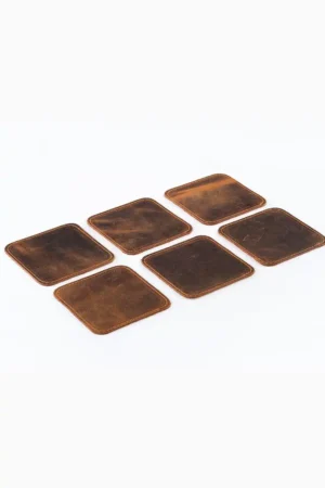 Six square brown leather coasters with rounded corners and contrast edge stitching arranged in a 2×3 layout on a white surface, photographed at a slight angle to show their texture and color variation.