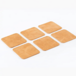 Set of six light brown leather coasters with stitched edges arranged on a light gray background.