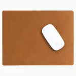 Light brown tan leather mouse pad with tone-on-tone perimeter stitching and rounded corners, with a white wireless mouse placed on the right side, top-down view on a white background.