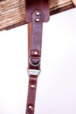 Close-up of the Garioch single camera strap connector with D-ring and metal hardware in dark brown leather.