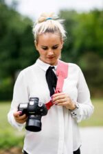 Photographer holding a camera while wearing the Garioch single camera strap in dark brown leather.