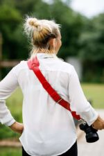 Rear view of a person wearing the Garioch single camera strap in dark brown leather over the shoulder.