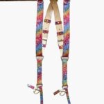 Rainbow multicolor leather dual camera harness with mosaic-textured snakeskin pattern, featuring natural vegetable-tanned leather padding, silver metal buckles, D-rings, and swivel snap hooks, hanging from a rustic wooden beam against a white background