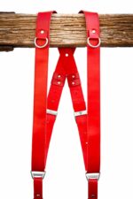 Red Campari leather camera harness displayed flat, showing full X-harness design with dual shoulder straps, square leather connectors, adjustable segments, and metal D-rings at chest attachment points