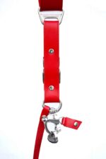 Close-up detail of Red Campari harness showing metal ring attachment, leather connector flap with rivets, and metal hardware for camera strap connection
