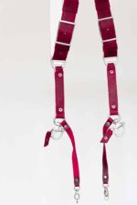 Close-up of the lower harness hardware showing both strap ends with silver snap shackle clips, lobster claw clasps, adjustable buckles, and riveted leather construction against a light background.