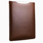 Vintage brown leather MacBook sleeve with patina finish, displayed at angle showing aged leather surface and protective curved shape