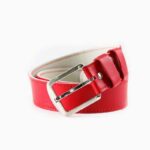 Red leather belt with silver buckle on white background