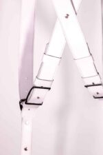 Close-up of crossed white leather harness straps with adjustable buckles and stitched edges.