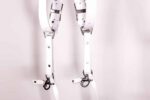 Close-up of the lower section of a white leather camera harness with silver swivel clasps and strap attachments.