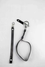 Black leather camera wrist strap shown as a loop with swivel clasp, laid flat on a white background.