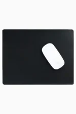 Black leather mouse pad with tone-on-tone perimeter stitching and rounded corners, with a white wireless mouse placed on the right side, top-down view on a white background.