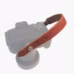 Tan premium leather camera hand strap shown attached to a camera body for comfortable wrist support.