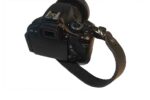 DSLR camera fitted with a black premium leather hand strap for a secure one-hand grip
