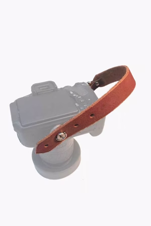 Tan premium leather camera hand strap shown attached to a camera body for comfortable wrist support.