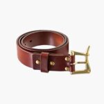 Brown leather belt rolled with brass buckle on white background