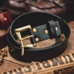 Close-up of black leather belt with brass buckle and rivets