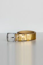 Gold padded leather trouser belt rolled on light background, silver buckle detail